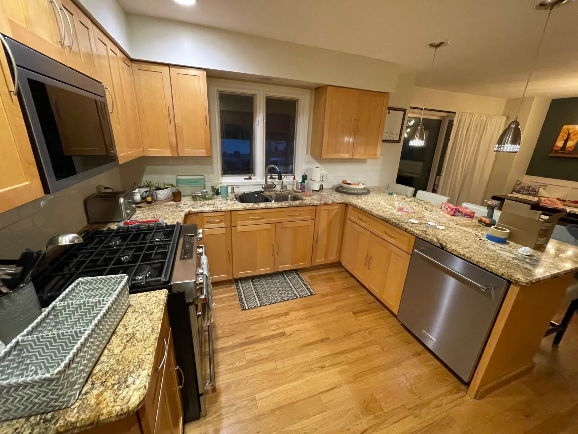 A spacious kitchen with wooden cabinets, granite countertops, stainless steel appliances, and dishes and food items placed on the counters. - Jeff Bryant Painting