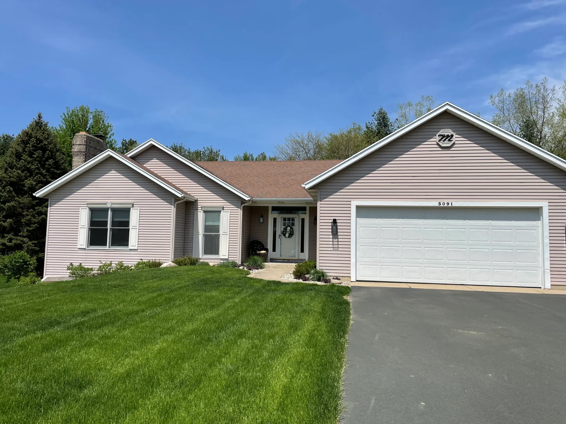 Single-story house with light siding, brown roof, two front windows, a two-car garage, and a well-maintained lawn under a clear blue sky. - Jeff Bryant Painting