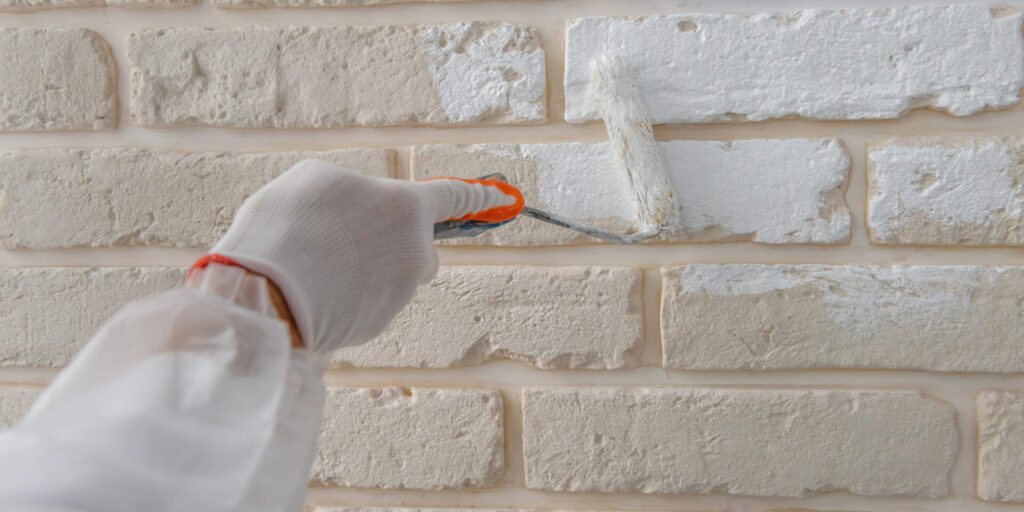 Homeowner carefully painting brick white, demonstrating proper technique for painting brick homes.