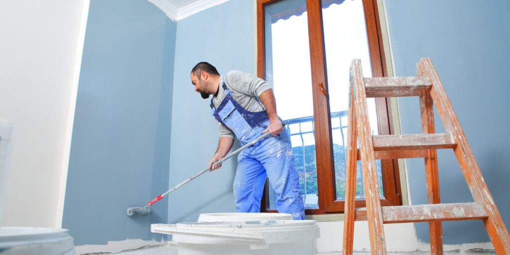 Professional painter applying fresh coat of paint to a room, illustrating the difference between professional painting vs DIY results.
