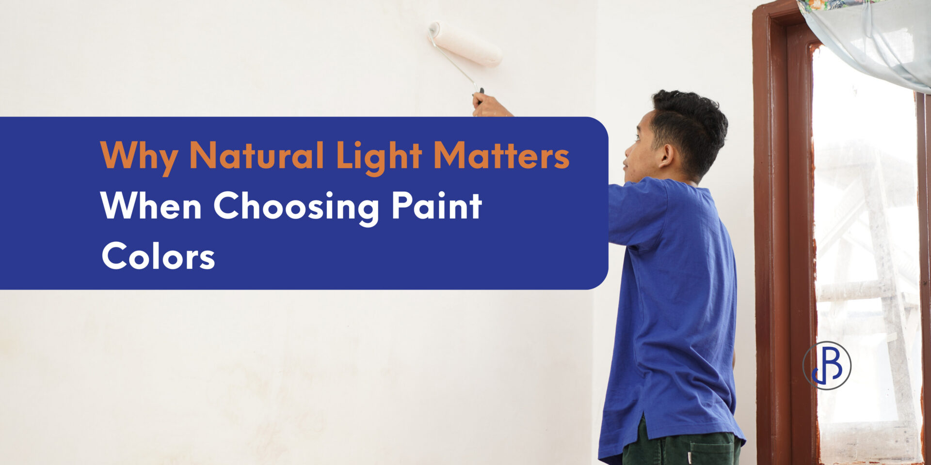 A person in a blue shirt paints a white wall with a roller near a window, letting in natural light; overlaid text reads, “Why Natural Light Matters When Choosing Paint Colors.”. - Jeff Bryant Painting